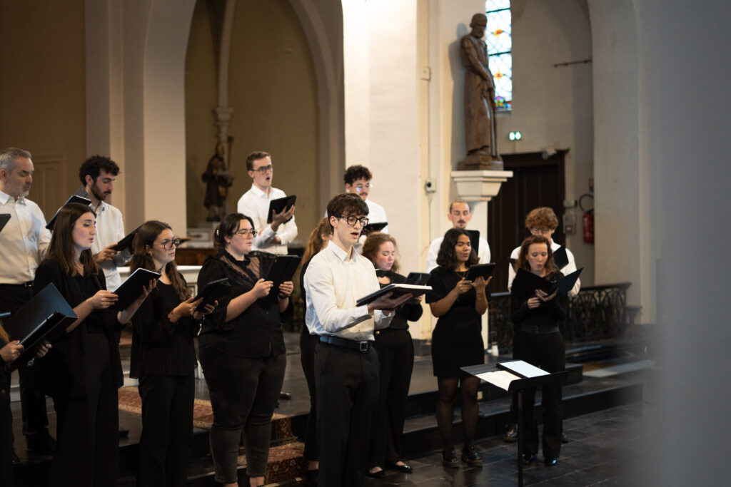 Un soliste chante au micro entouré du chœur, à l'église de Chéreng, lors du concert partagé avec l'ensemble vocal Résonance.