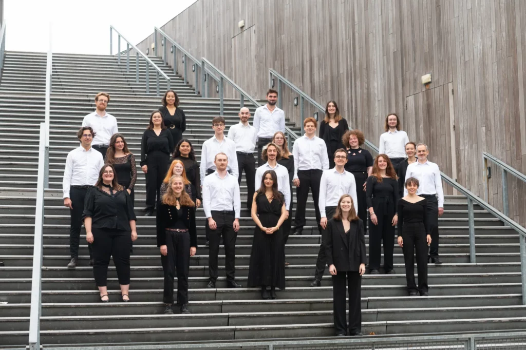 Les choristes du chœur Ineffable en tenue de concert noir et blanc, alignés sur le grand escalier du Colisée de Lambersart